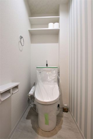 ストライプのアクセントクロス♪トイレの上部には棚があり、トイレットペーパーなどのストックを置くことが